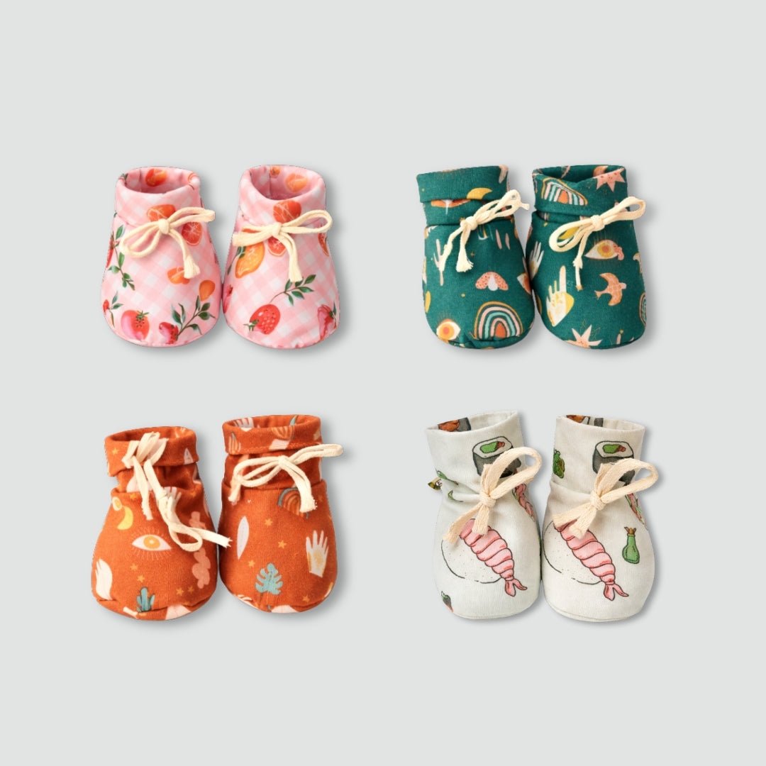 A bundle of soft, white cotton booties for babies, featuring a comfortable and secure fit.